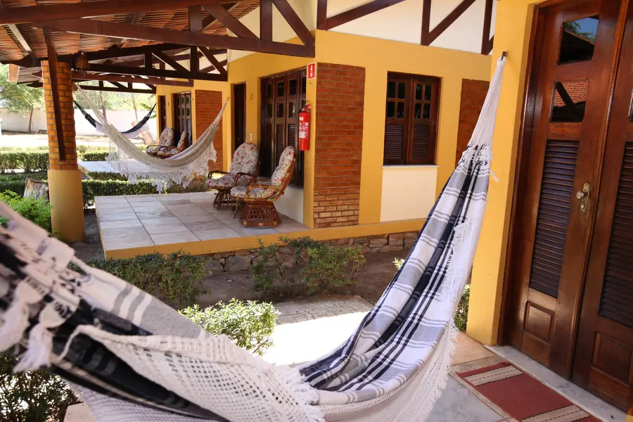Fachada dos chalés com rede armada na varanda.
