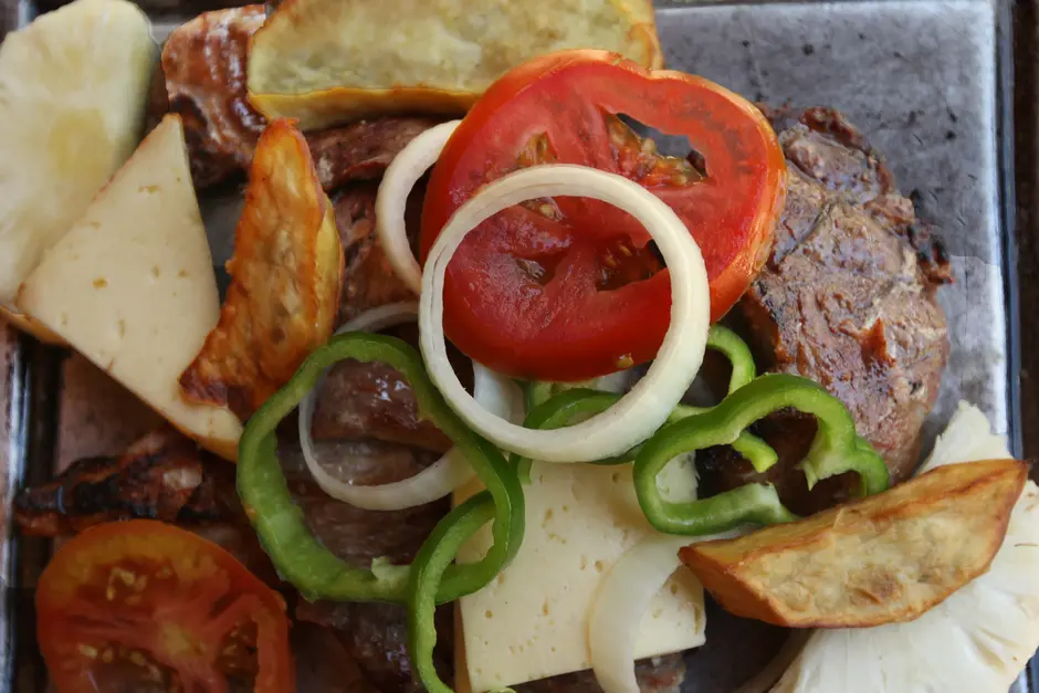 Grelhado servido com tomate, pimentão e cebola.