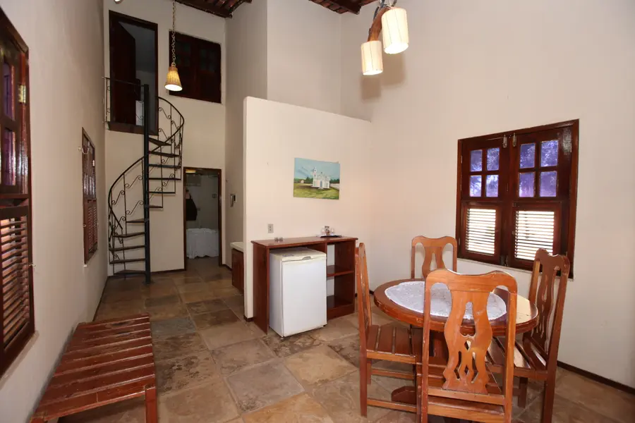 Sala do chalé superior com pé-direito duplo e escada caracol.
